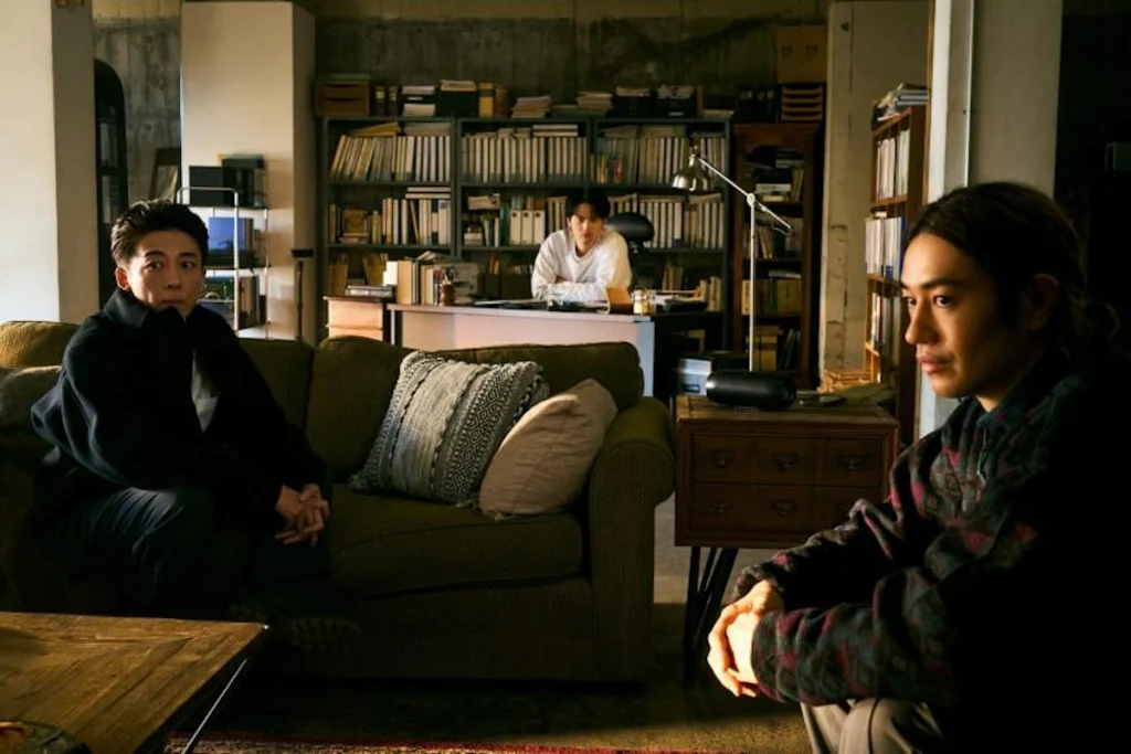 薄暗い部屋でテーブルを囲み、深刻な表情で話し合う3人の日本人男性。15年前の秘密と友情、家族を守る選択に葛藤するイメージ。